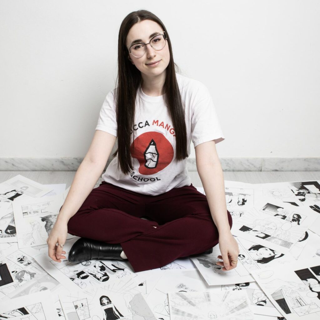 Caterina Rocchi - seduta in mezzo a tante tavole manga
