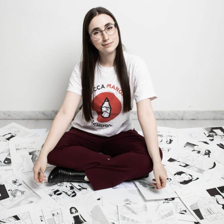 Manga Level Up 2 Caterina Rocchi - seduta in mezzo a tante tavole manga